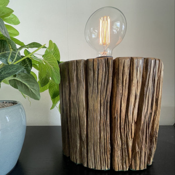 Round telegraph jarrah post upcycled into wood table lamp with addition of edison bulb, lit, vertical erosion grooves, crafted by shades at grays.