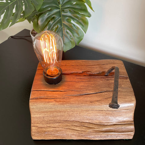 Rustic reclaimed wharf timber table lamp crafted by shades at grays, nz, with original iron nail, lit.
