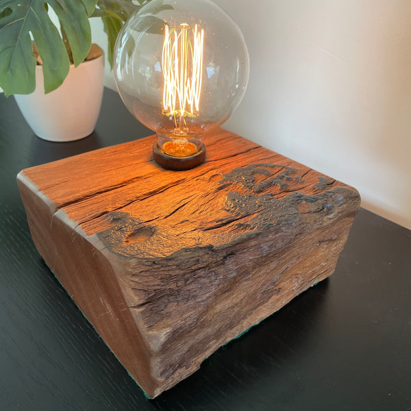 Unique wood table lamp crafted by shades at grays from 100 year old reclaimed wharf timber, lit, close up of polished side grain and front live edge.