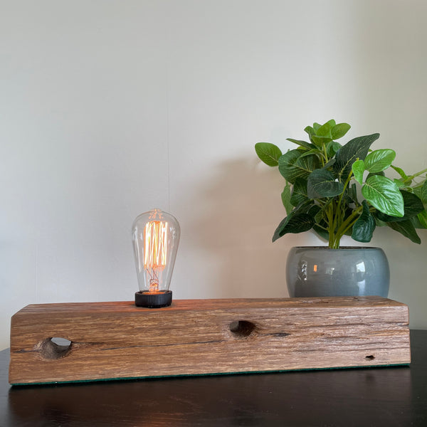 Wood table lamp crafted by shades at grays from telegraph cross piece, front view, lit.