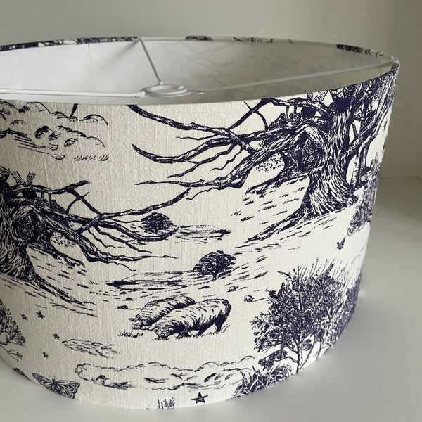 Large barrel ceiling lampshade with pastoral scene etched in ink blue on soft white textured background, cose up, unlit.