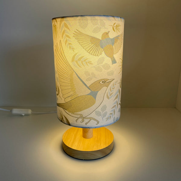 Small table lamp with handcrafted lampshade with Jade Ell's Tauhou Bird Pattern Pale fabric, lit.