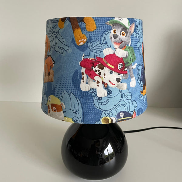 Lamp with a colorful paw-themed shade on a white background