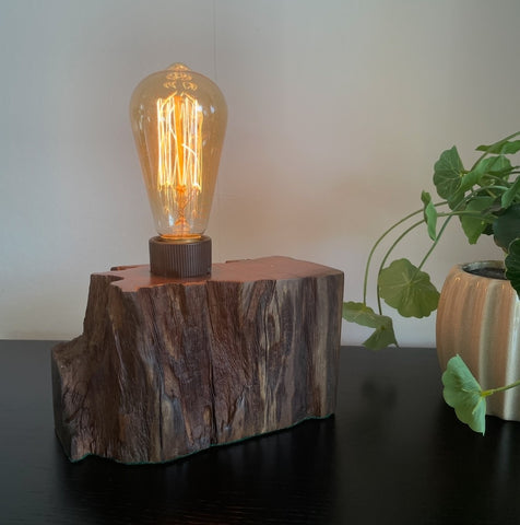 Small wood table lamp crafted from upcycled wharf timber, front view with original erosion grooves and smooth top with the addition of an edison bulb, lit made by shades at grays.