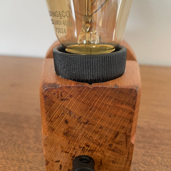 Small carpenters plane upcycled by shades at grays with added replica edison light bulb, unlit, back view.