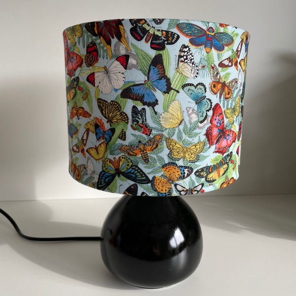 Small drum hand crafted fabric light shade, unlit on black base.