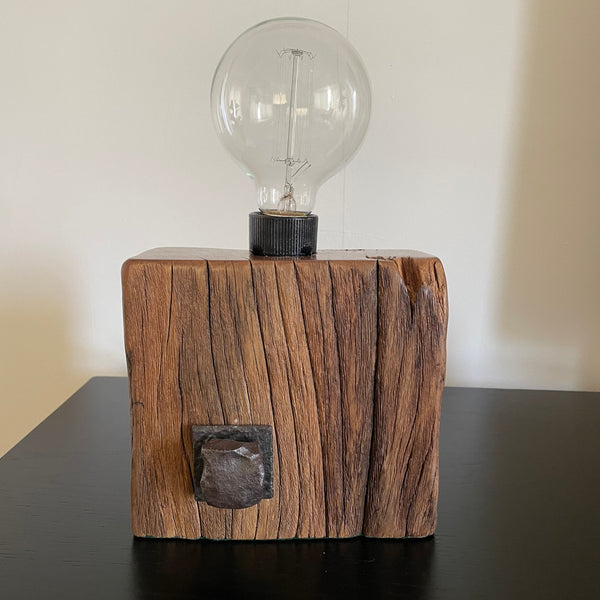 Smalll wood lamp crafted from recycled wharf timber with original bolt and edison bulb, unlit by shades at grays.