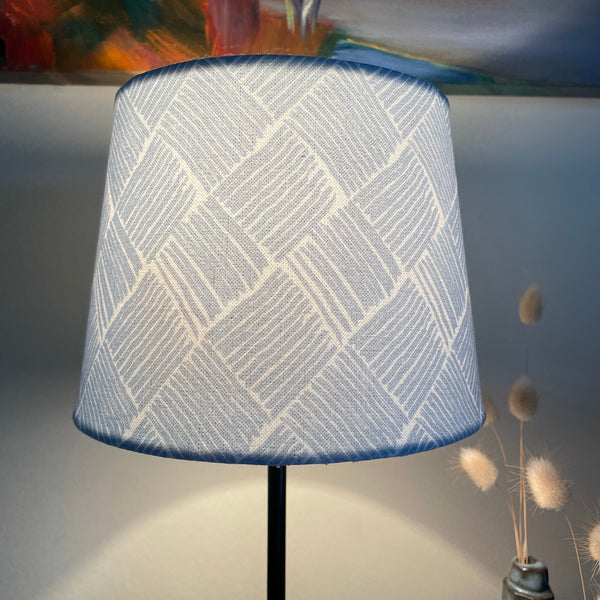 Small tapered handcrafted fabric lamp shade, lit.