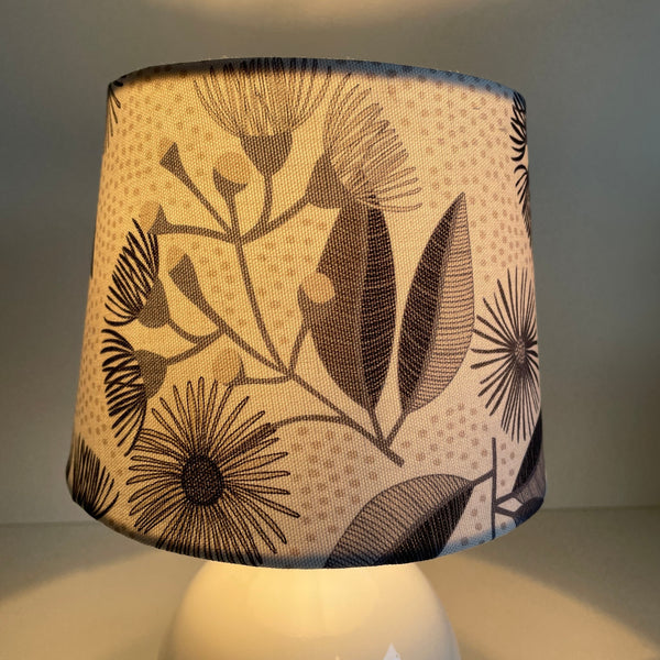 Small tapered lampshade by shades at grays with eucalyptus blossom fabric, lit.