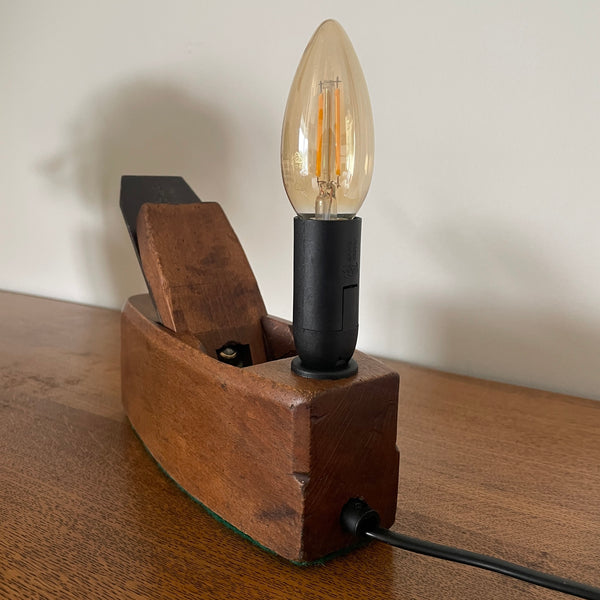 Wooden lamp with a lit bulb on a wooden surface