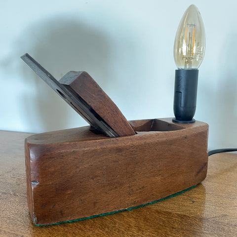 Wooden plane lamp with a light bulb on a wooden surface