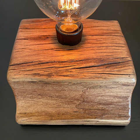 Smooth polished wood with original erosion and replica edison bulb, lit, bu shades at grays.