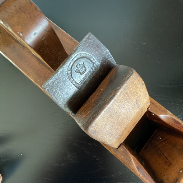 Soft brown polished wood, with original markings and branding mark on cutting blade, close up.