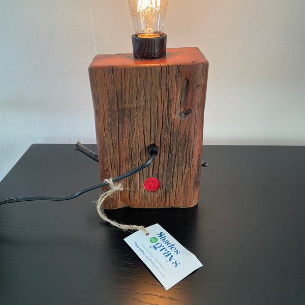 Table lamp, crafted from reclaimed wharf timber, reddish colour wood with deep marks of erosion, made by shades at grays, nz, back view.