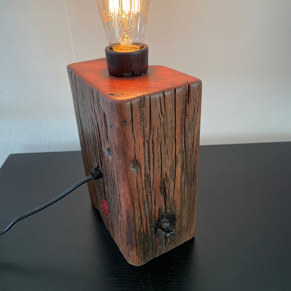 Table lamp, crafted from reclaimed wharf timber, reddish colour wood with deep marks of erosion, unlit, made by shades at grays, wellington, side and back view.