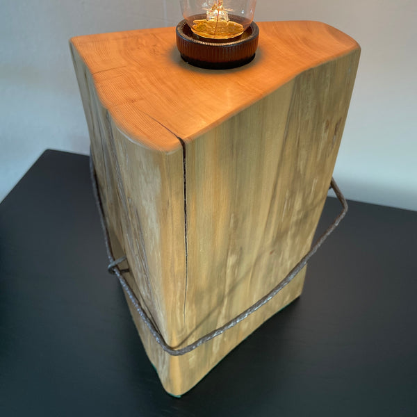 Table lamp crafted by shades at grays, nz, from old tōtara fence post with original iron, close up of smooth top and side.