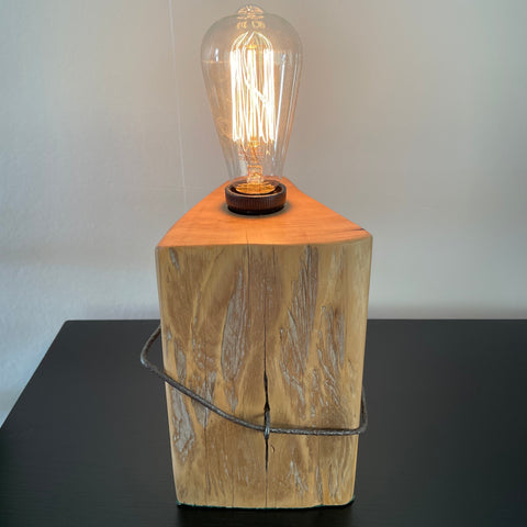 Table lamp crafted by shades at grays, nz, from old tōtara fence post with original iron, front view, lit.