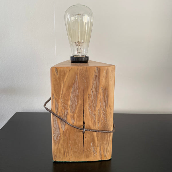 Table lamp crafted by shades at grays, nz, from old tōtara fence post with original iron, front view, unlit.