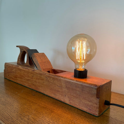 Wooden lamp with a vintage-style light bulb on a wooden surface.