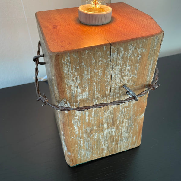 Table lamp crafted by shades at grays from old tōtara fence post, close up of original barb wire and wood grain.