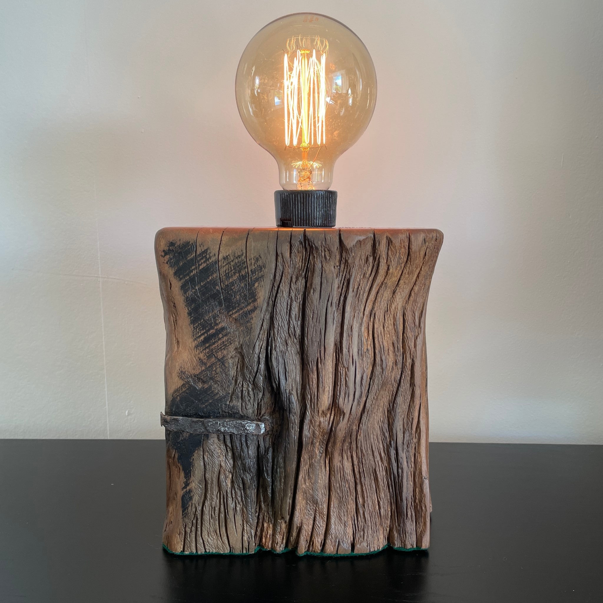 Table lamp crafted from original wharf timber by shades at grays nz, with original nail, lit.