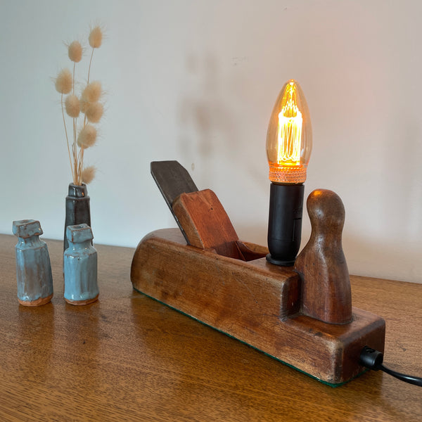Table lamp handcrafted by shades at grays from authentic carpenter's plane, with LED candle E14 bulb, lit.