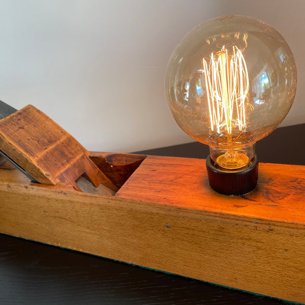 Table lamp made from authentic wood plane by shades at grays, nz, close up of warm golden wood, lit.