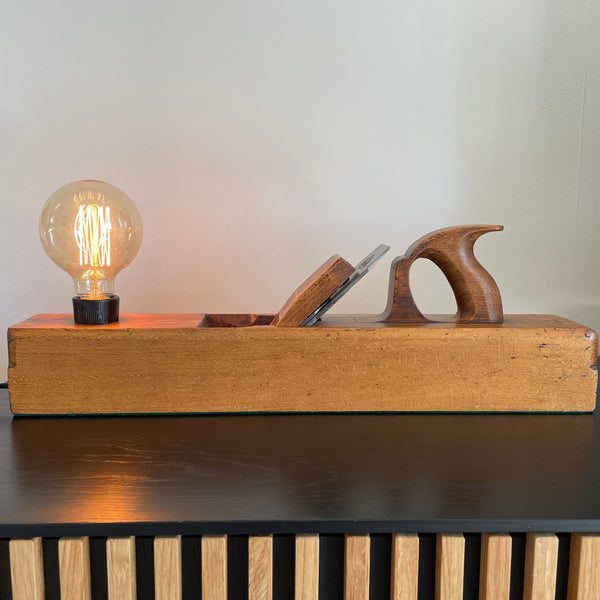 Table lamp made from authentic wood plane by shades at grays, nz. Lit.