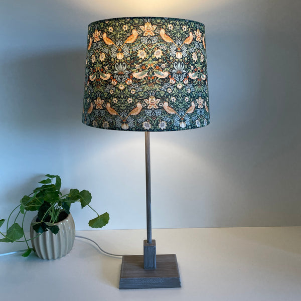 Tapered 24 lampshade with strawberry thief mini marine fabric, lit, on gray washed base, lampshade crafted by shades at grays.