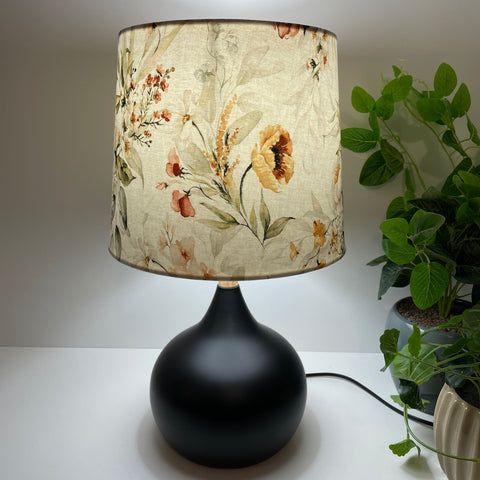 Tapered 23 lightshade nz with golden bouquet fabric, lit, on black base, by shades at grays