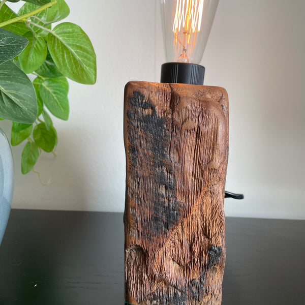 Reclaimed wood table lamp, side view with retained tar and erosion marks, side view with glimpse of black lead and edison bulb, lit, created by Shades at Grays