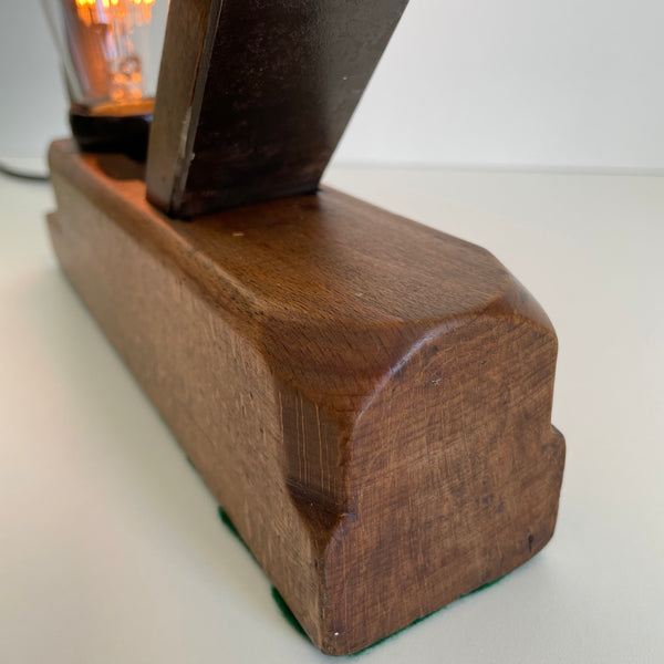 Toe of wooden table lamp crafted from old carpenter's wood block plane, with edison bulb, lit.