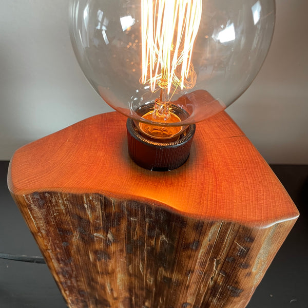 Tortoiseshell markings on old tōtara fence post upcycled to unique wood lamp, close up of polished top.