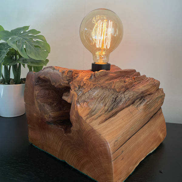 Totara wood lamp crafted by shades at grays, polished with natural bees wax, with eroded hole and smooth grain, side and front view, lit.
