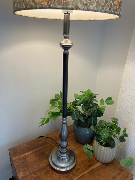 Toulouse lamp stand in black and pewter, with lit lampshade, close up.
