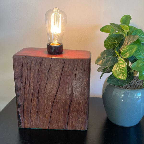 Hand crafted wood lamp created from reclaimed wharf timber, front view and smooth polished top, by shades at grays, lit.