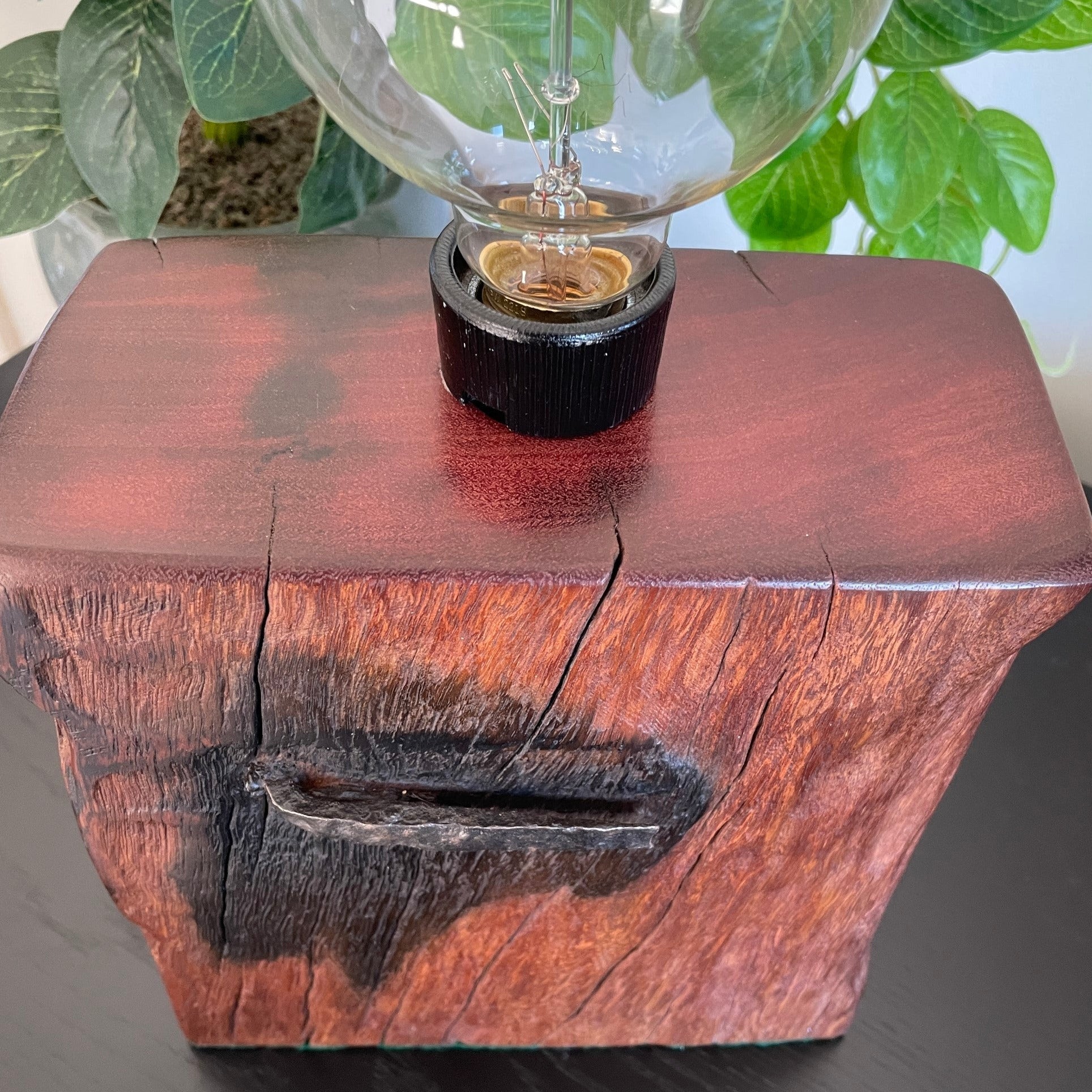 Deep red wood of table lamp handcrafted from 100 year old wharf timber by shades at grays, unlit.