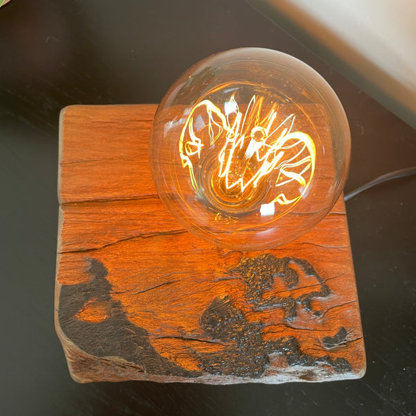 Unique wood table lamp crafted by shades at grays from 100 year old reclaimed wharf timber, lit, top view and close up of replica edison bulb.