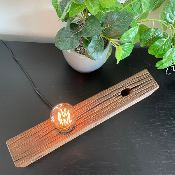 Wood table lamp crafted by shades at grays from telegraph cross piece, lit, top view.