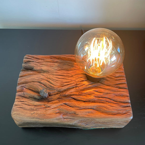 Upcycled wharf timber table lamp, handcrafted by shades at grays, top view of erosion lines and original nail, with edison lamp, lit.