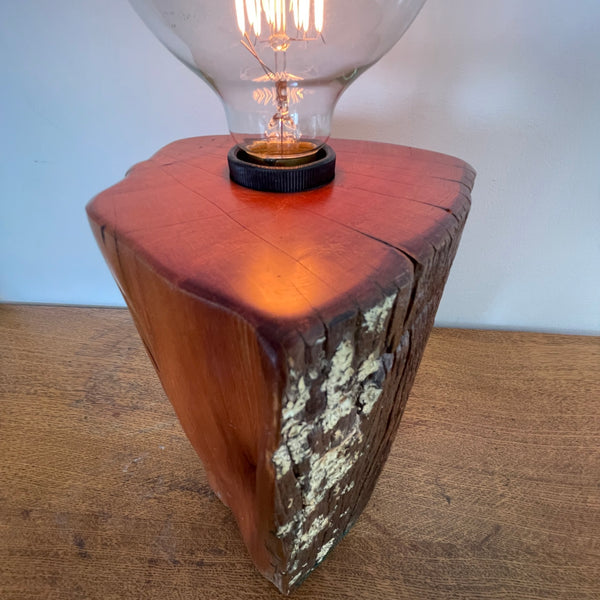 Upcycled wood lamp handcrafted by shades at grays from vintage totara post with lichen smooth top and side views, lit.