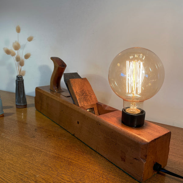 Vintage carpenters plane with replica edison bulb, lit, back and side view with black lead, crafted by shades at grays.