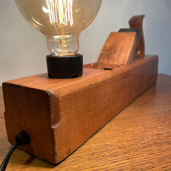 Vintage carpenters plane with replica edison bulb, lit, close up of smooth sides, polished with natural bees wax,  crafted by shades at grays.