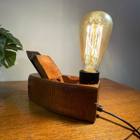 Vintage carpenter's plane, small with edison bulb, lit with black lead, and bees wax polished shides, by shades at grays.