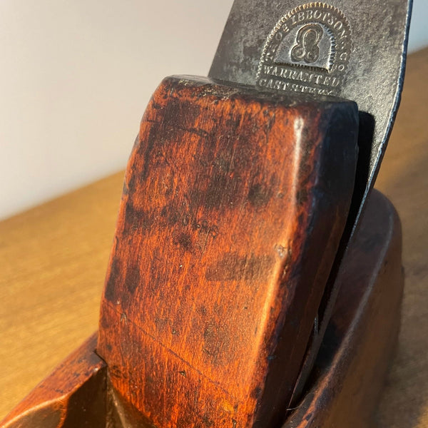 Deep warm brown beech wood table lamp, close up of mid-section and cutting blade brand of authentic carpenters plane.