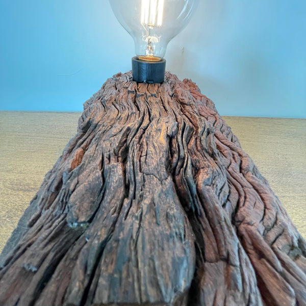 Upcycled wood table lamp, wavy patterned erosion grooves, and additional edison bulb, lit by Shades at Grays long view of top.