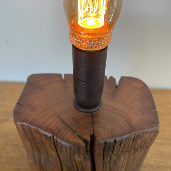 Wharf timber table lamp with candle bulb and deep brown grain, upcycled by shades at grays, smooth polished top.