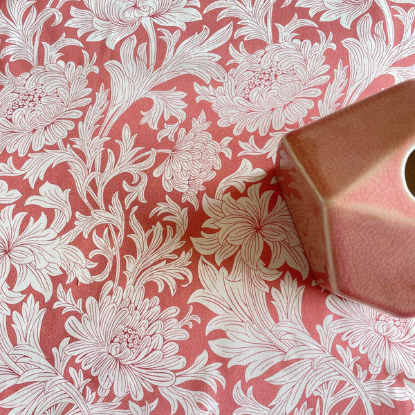 William Morris wandle chrysanthemum fabric sample with white blooms and leaves on a rose pink background, pink vase on fabric for colour comparison.
