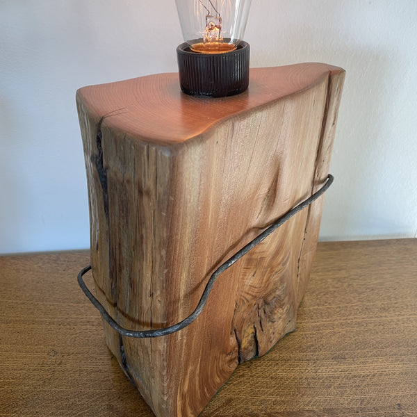 Wood table lamp crafted from vintage tōtara fence post with original wire and replica edison bulb, lit, polished smooth edges, handcrafted by shades at grays.