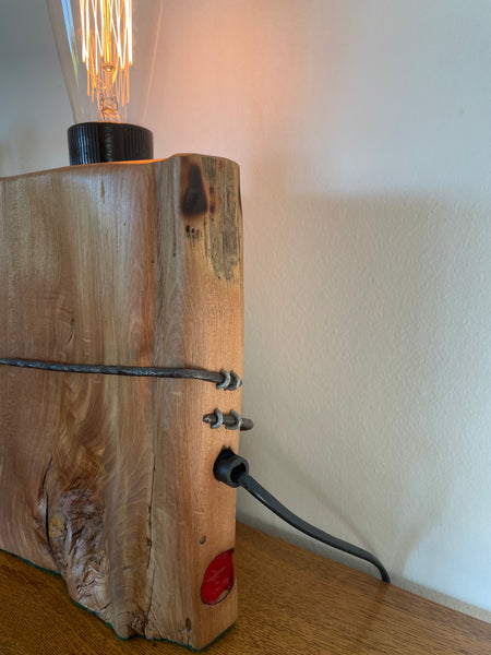 Wood table lamp crafted from vintage tōtara fence post with original wire and replica edison bulb, lit, side and back view, handcrafted by shades at grays.